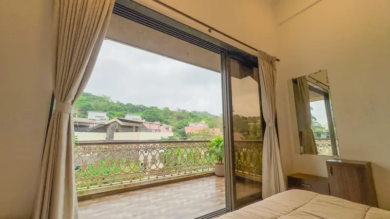 Bedroom window opening onto a balcony and hills